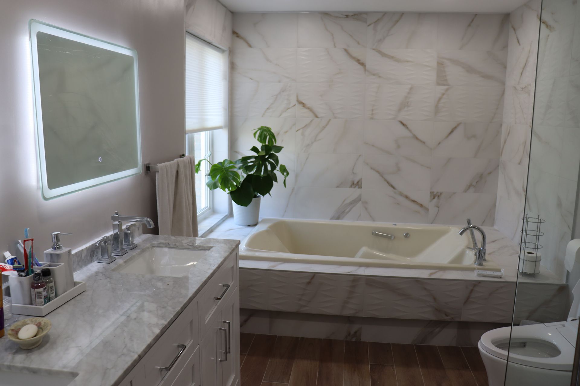 A bathroom with a tub , sink , toilet and mirror.