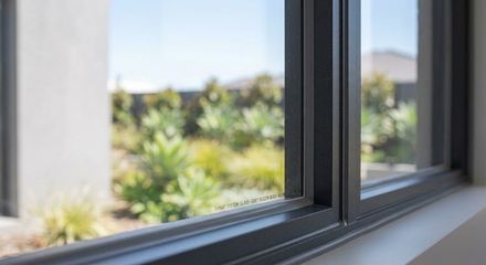 Bright white windowsill by an open window with sunlight and a blurred green view outside