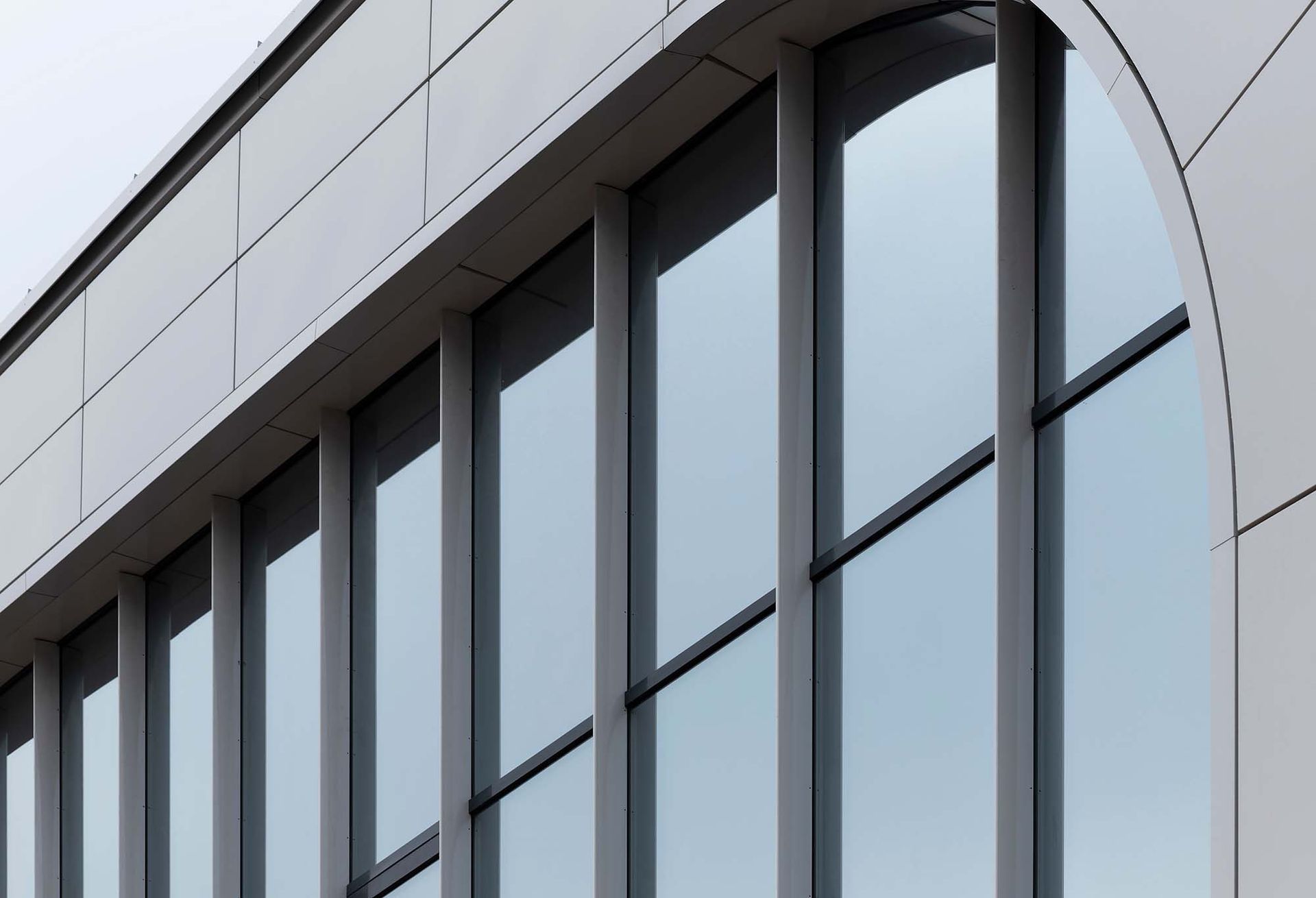 Modern building facade with tall reflective windows and white curved paneling