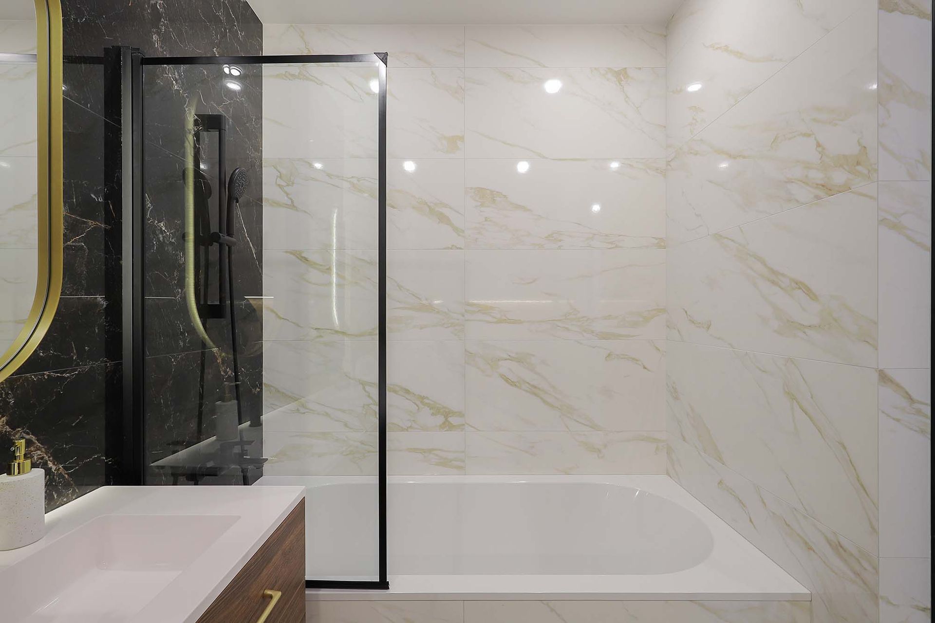 Modern bathroom with glass shower, marble walls, bathtub, and vanity sink