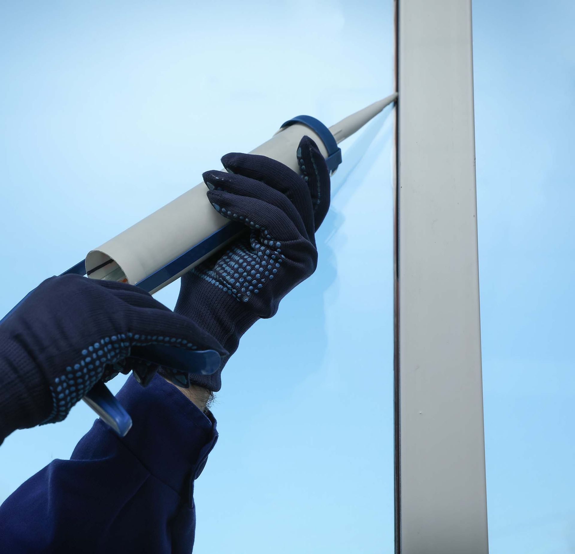 Gloved hands tightening a rope around a metal pole against a blue sky