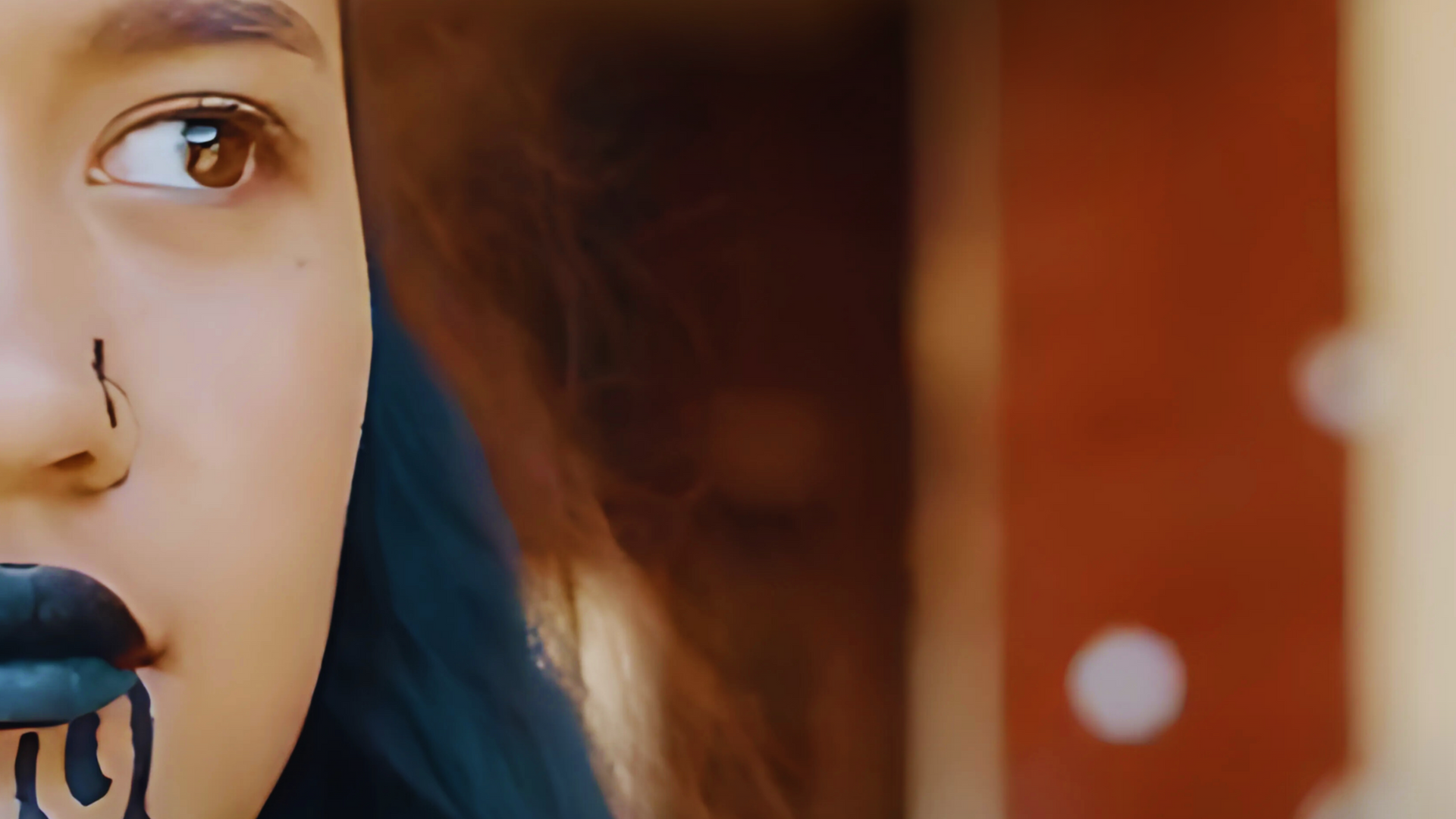 Close-up of a person with a nose ring singing into a microphone, with a warm blurred background