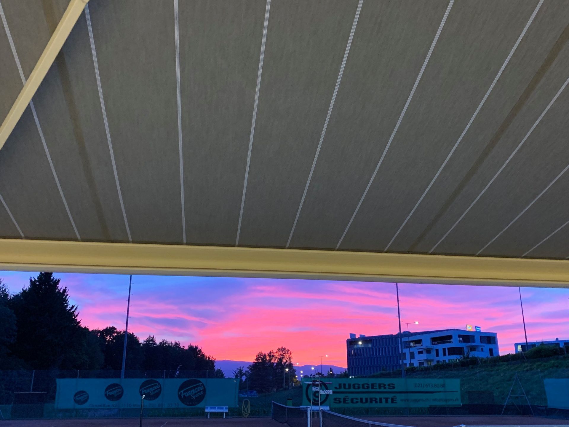 Une vue d'un coucher de soleil sur un court de tennis sous un auvent