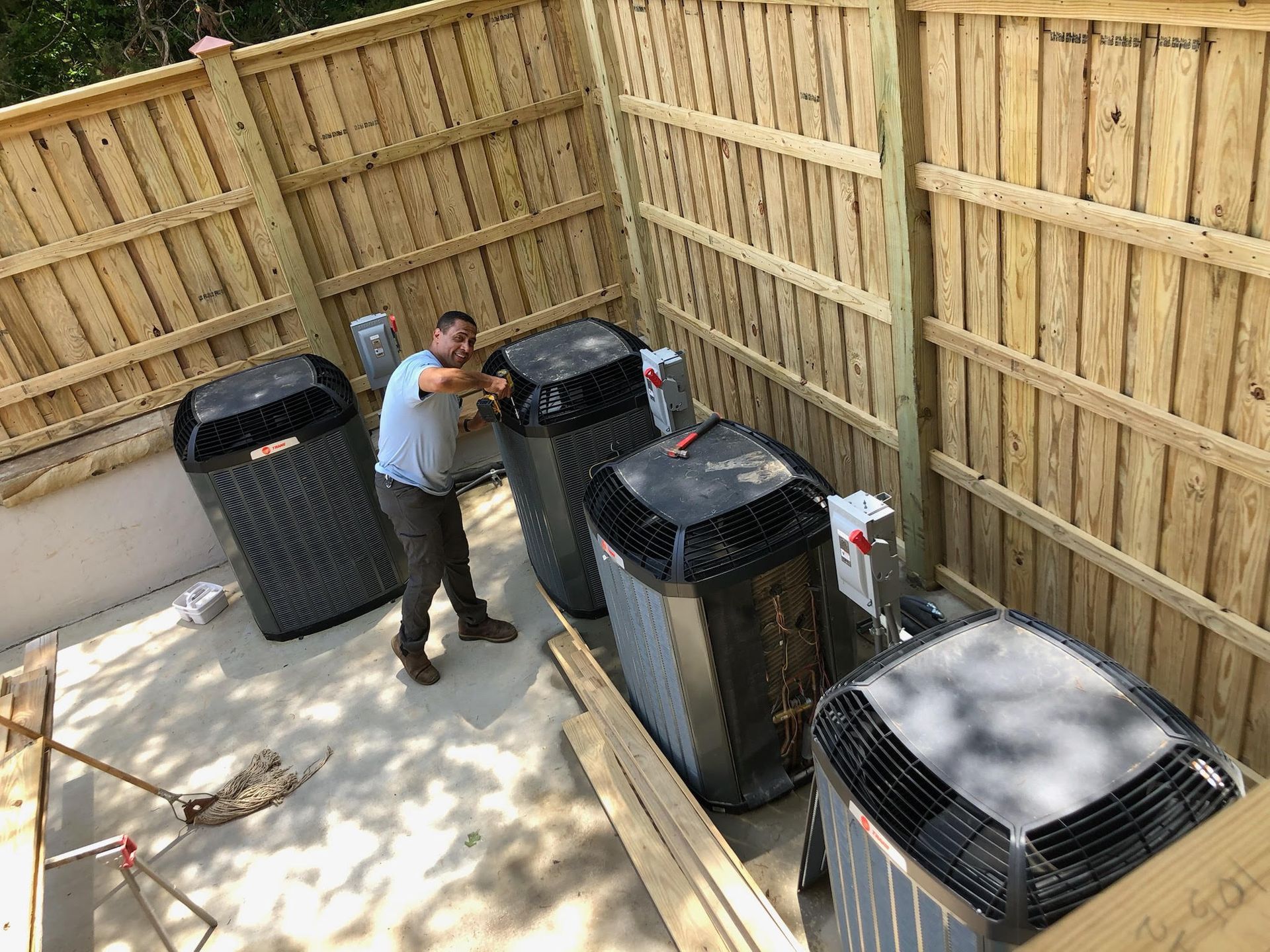 Technician inspecting large outdoor HVAC units in a fenced utility area