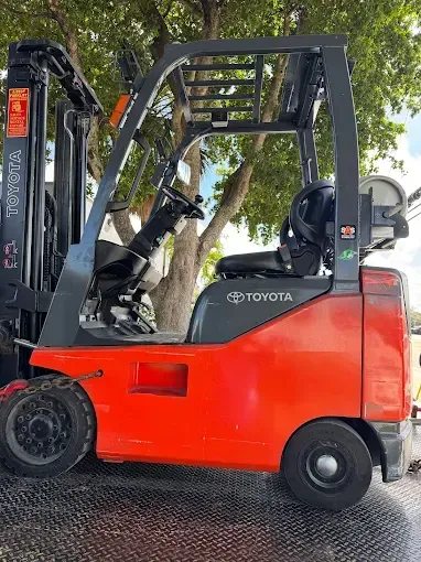 Red Toyota forklift on a surface, outdoors.