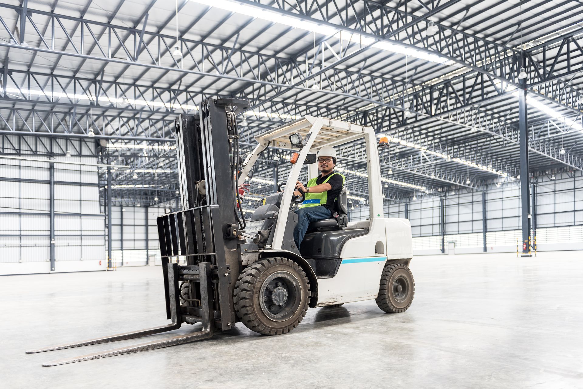 Forklift operator in a warehouse, wearing safety gear. Forklift operator in a warehouse, wearing safety gear.
