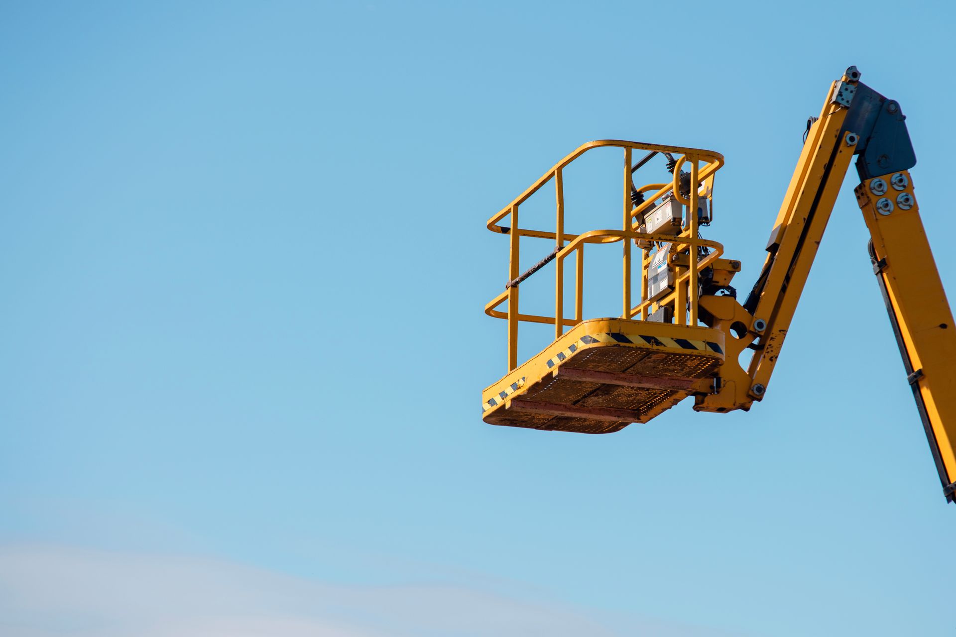 Yellow aerial work platform lift raised against a clear blue sky. Yellow aerial work platform lift raised against a clear blue sky.
