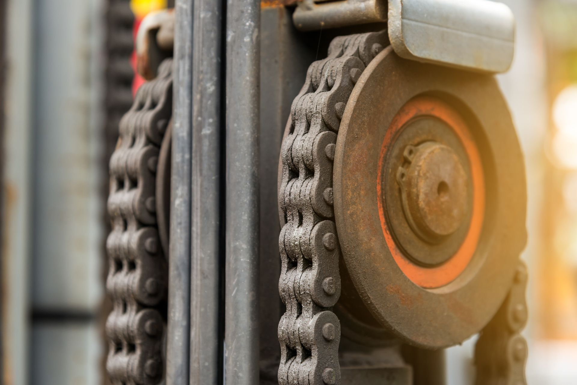 Forklift truck part with a worn chain and metal wheel assembly.