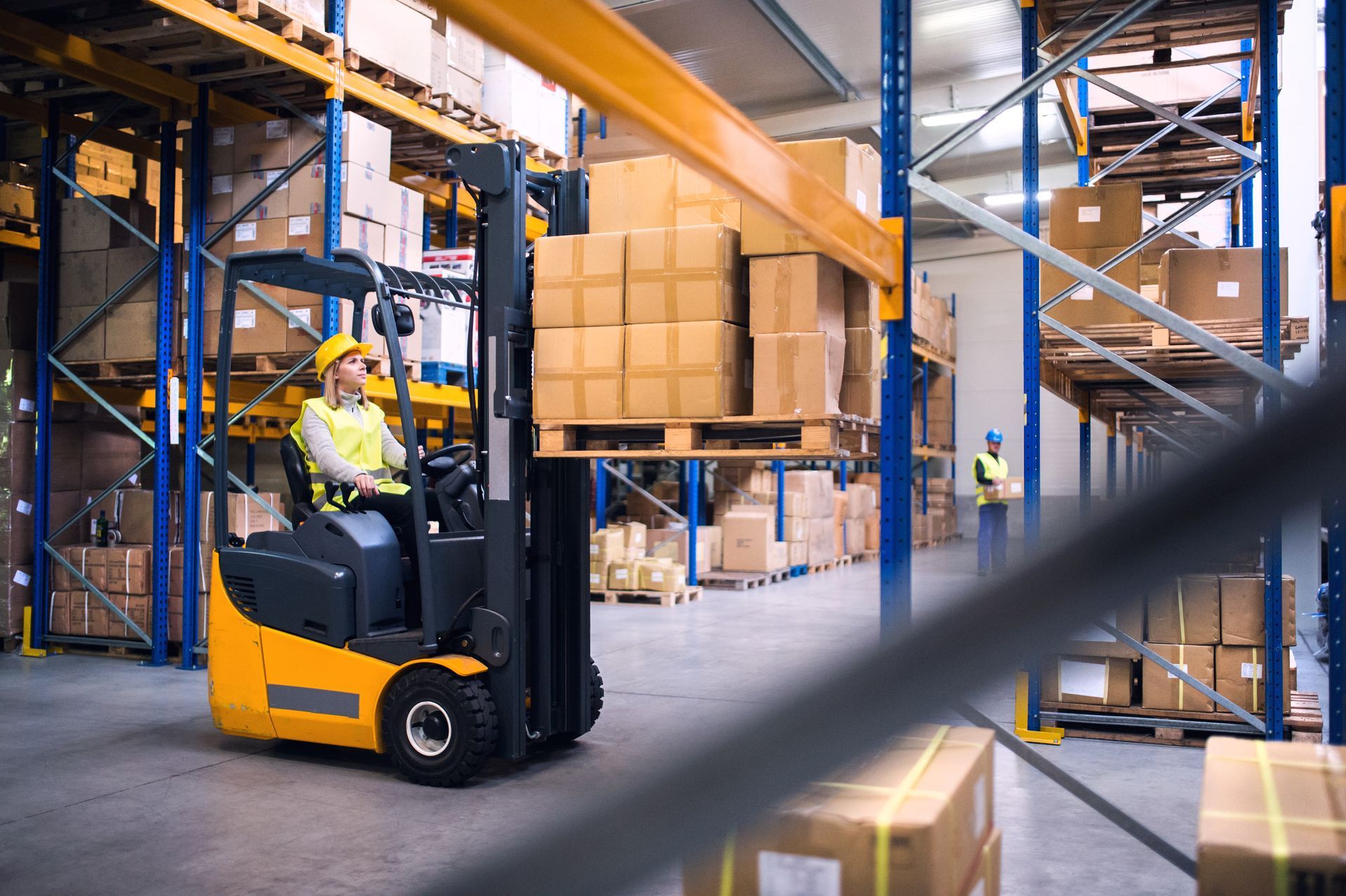 Forklift operator in a warehouse, lifting a pallet of boxes onto a high shelf. Forklift operator in a warehouse, lifting a pallet of boxes onto a high shelf.