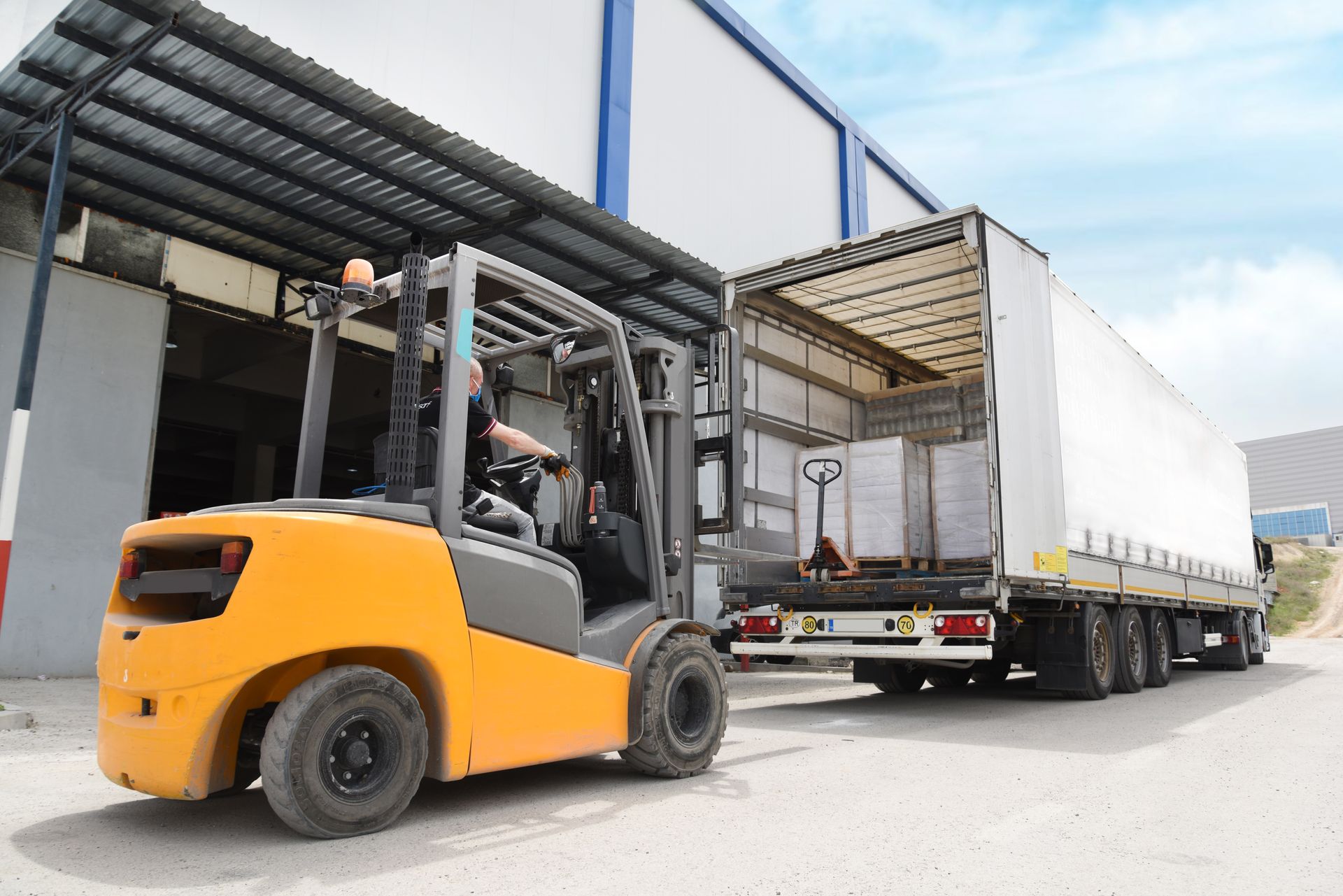 Yellow forklift loading a white trailer at a warehouse. Yellow forklift loading a white trailer at a warehouse.