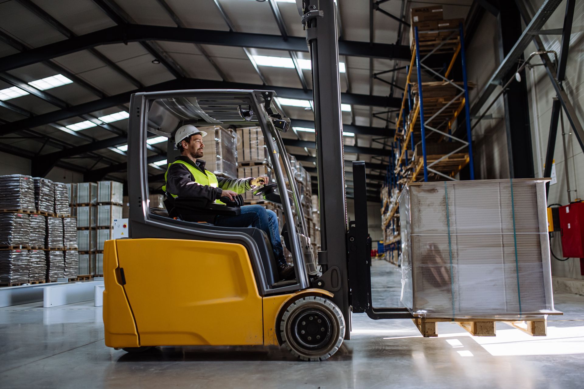 Warehouse worker operating a yellow forklift, transporting a pallet of goods. Warehouse worker operating a yellow forklift, transporting a pallet of goods.