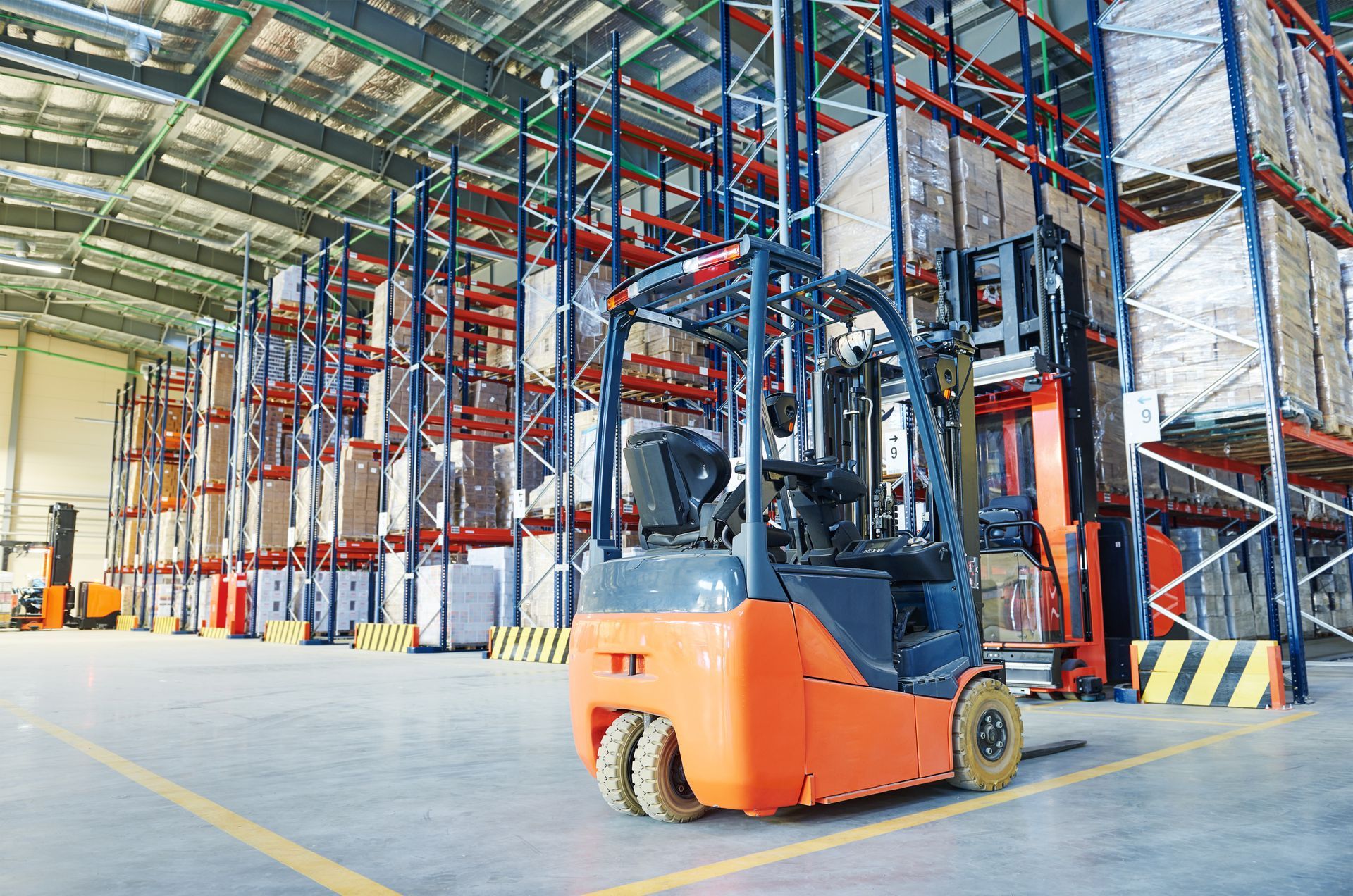 Orange forklift in a warehouse with tall shelves of packaged goods. Orange forklift in a warehouse with tall shelves of packaged goods.