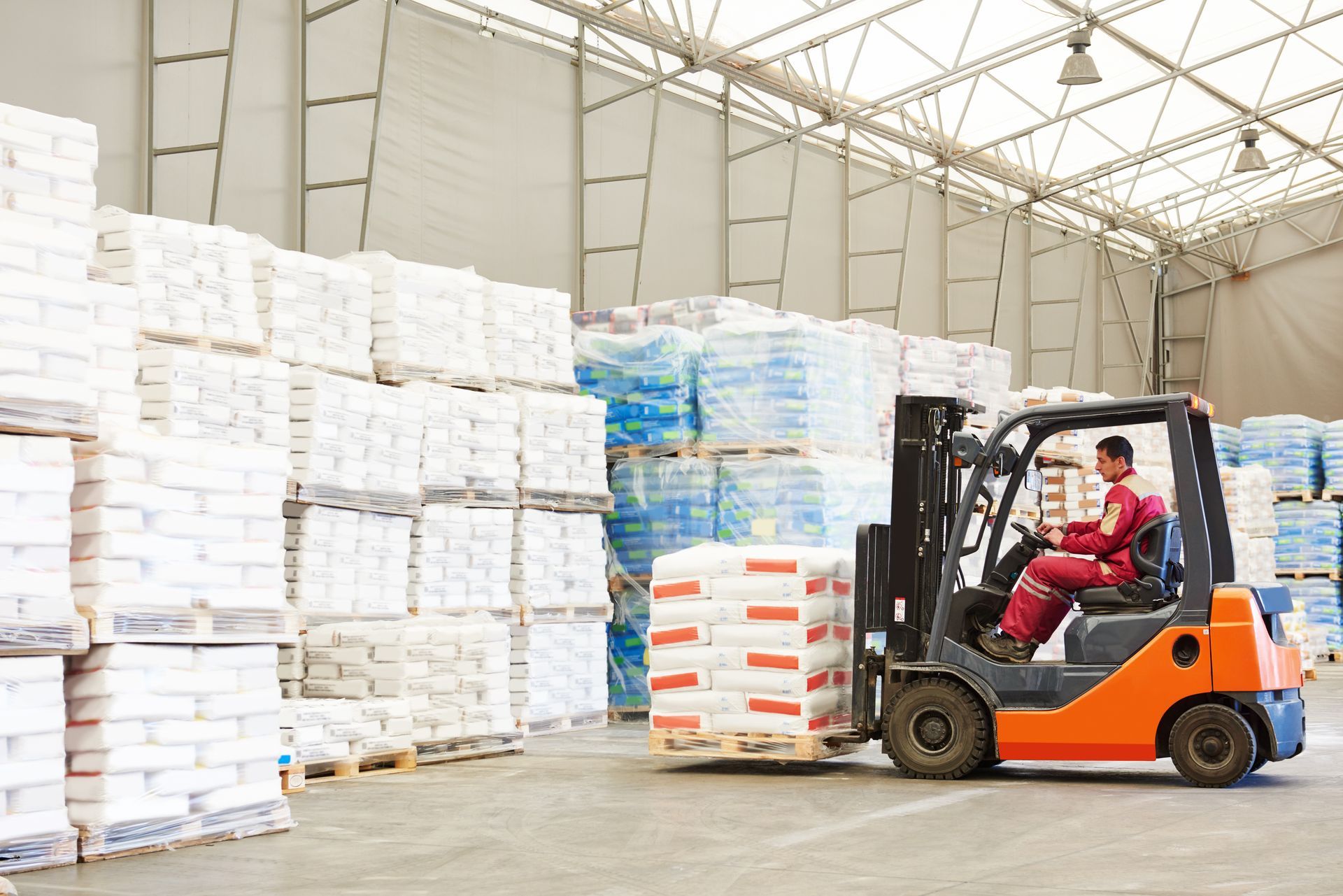 Forklift operator in a warehouse moves pallets of bagged product. Forklift operator in a warehouse moves pallets of bagged product.