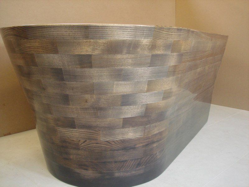 A wooden bathtub is sitting on a white table