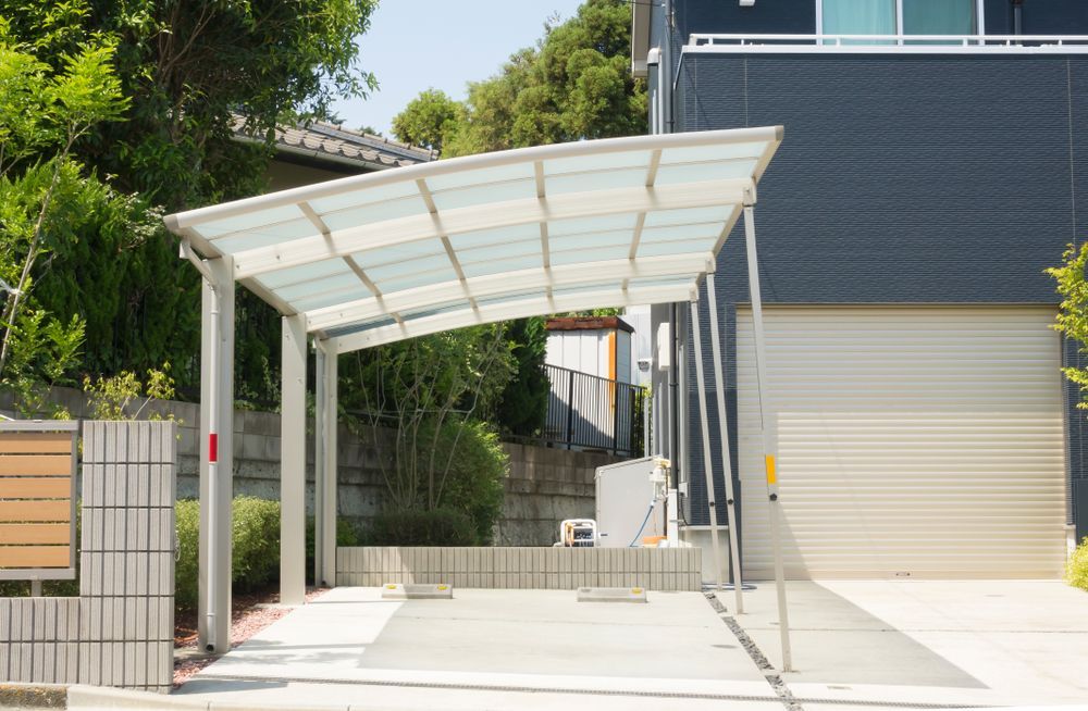Carport Next to a Dark Gray House With a White Garage Door — ShedBoss in Atherton, QLD