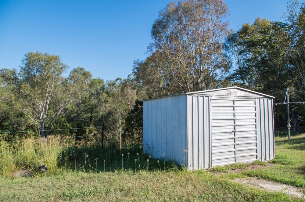 Metal Shed in a Grassy Area With Trees in the Background — ShedBoss in Atherton, QLD