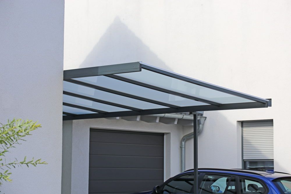 Carport With Clear Roof Over a Gray Garage Door — ShedBoss in Ravenshoe, QLD 