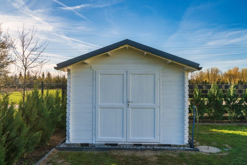 White Wooden Garden Shed With Double Doors on a Grassy Lawn Under a Blue Sky — ShedBoss in Tolga, QLD