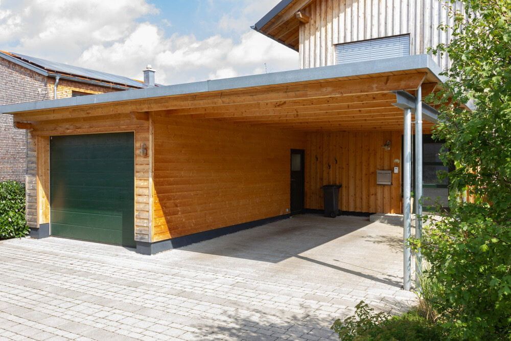 Wooden Carport With a Green Garage Door and a Paved Driveway — ShedBoss in Malanda, QLD 