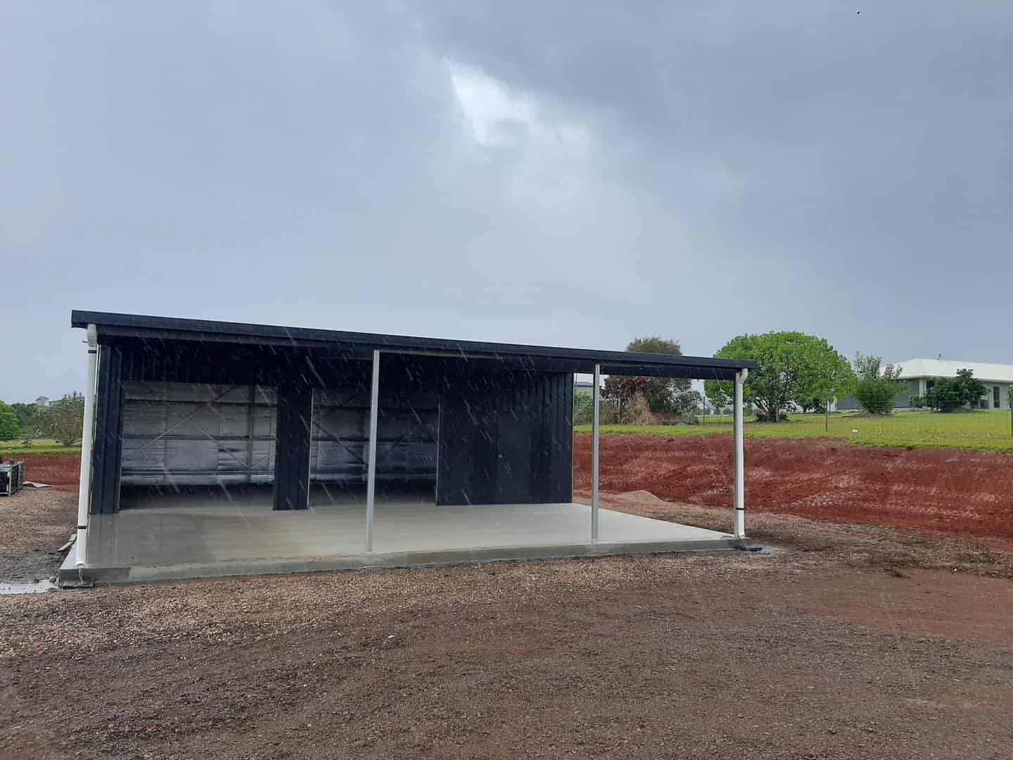 A Black Shelter With a Concrete Base in the Rain — ShedBoss in Atherton, QLD