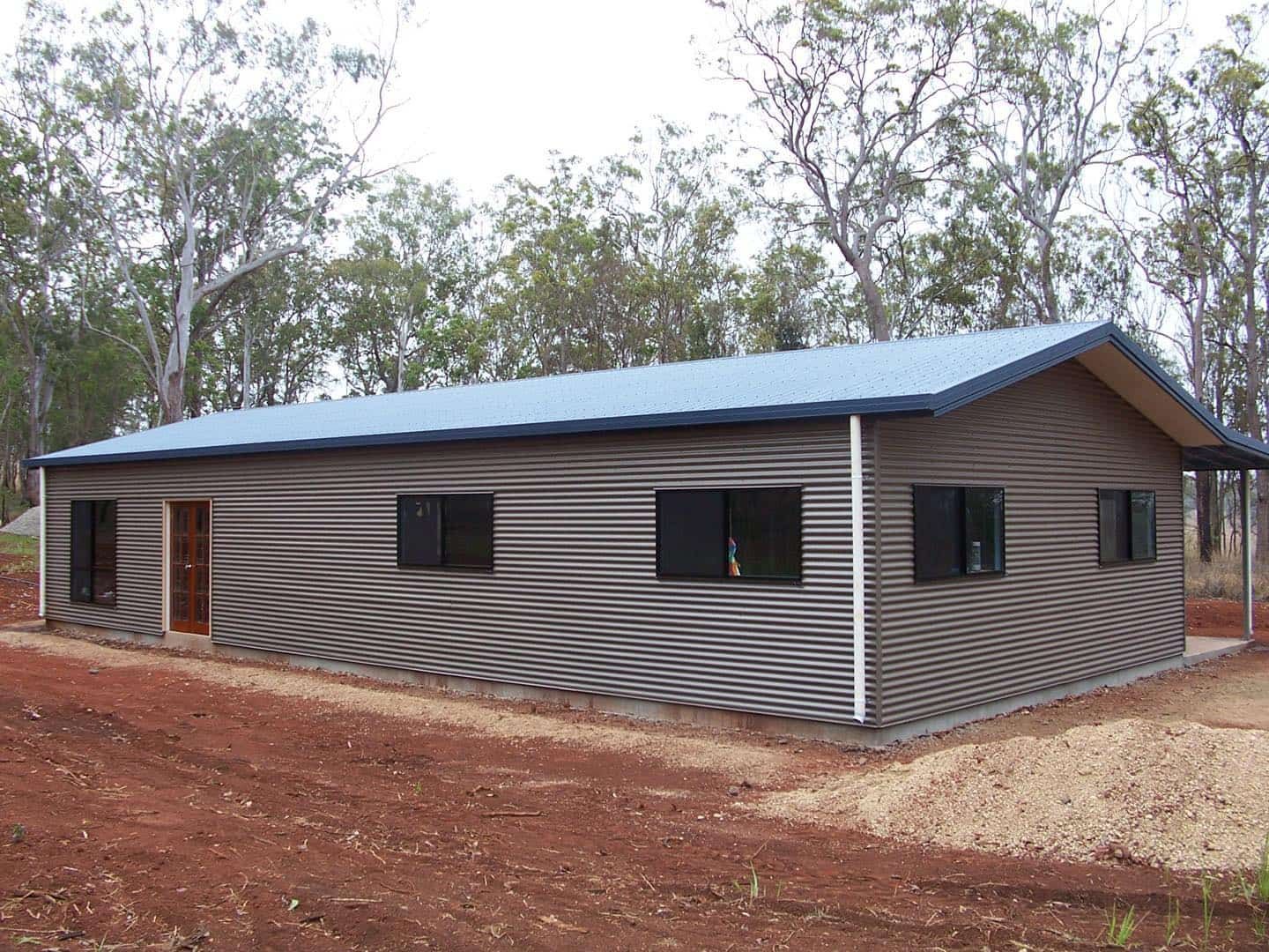 Metal-clad Building With a Blue Roof and Dark Windows in a Wooded, Brown Earth Setting — ShedBoss in Atherton, QLD