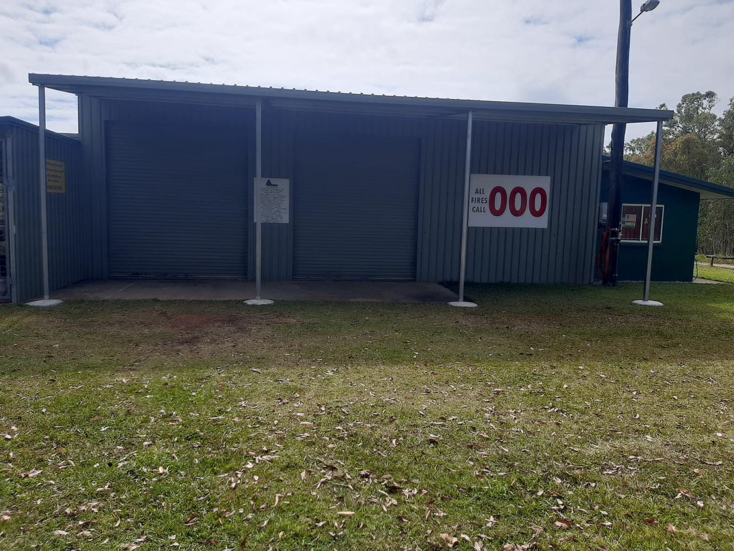 Gray Building With a Covered Walkway; Sign Indicates Emergency Number 000 — ShedBoss in Atherton, QLD