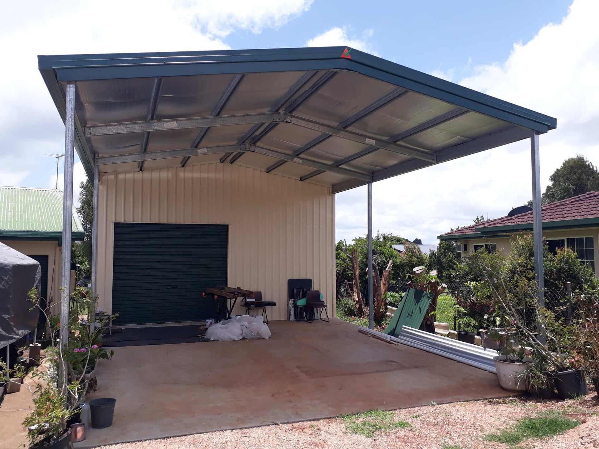 Carport Attached to a Garage With a Dark Green Garage Door — ShedBoss in Atherton, QLD