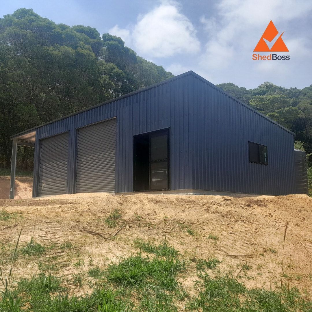 Blue Metal Shed With Two Garage Doors and a Door on a Hillside — ShedBoss in Atherton, QLD