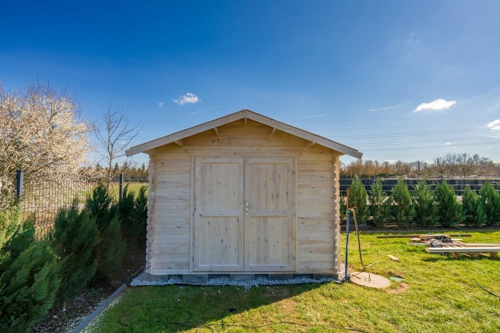 Wooden Shed With Double Doors on Green Grass Under Blue Sky — ShedBoss in Ravenshoe, QLD 