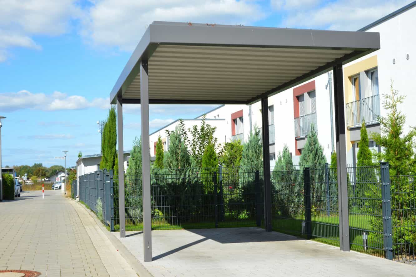Gray Carport in Front of Bushes on a Paved Driveway — ShedBoss in Mareeba, QLD