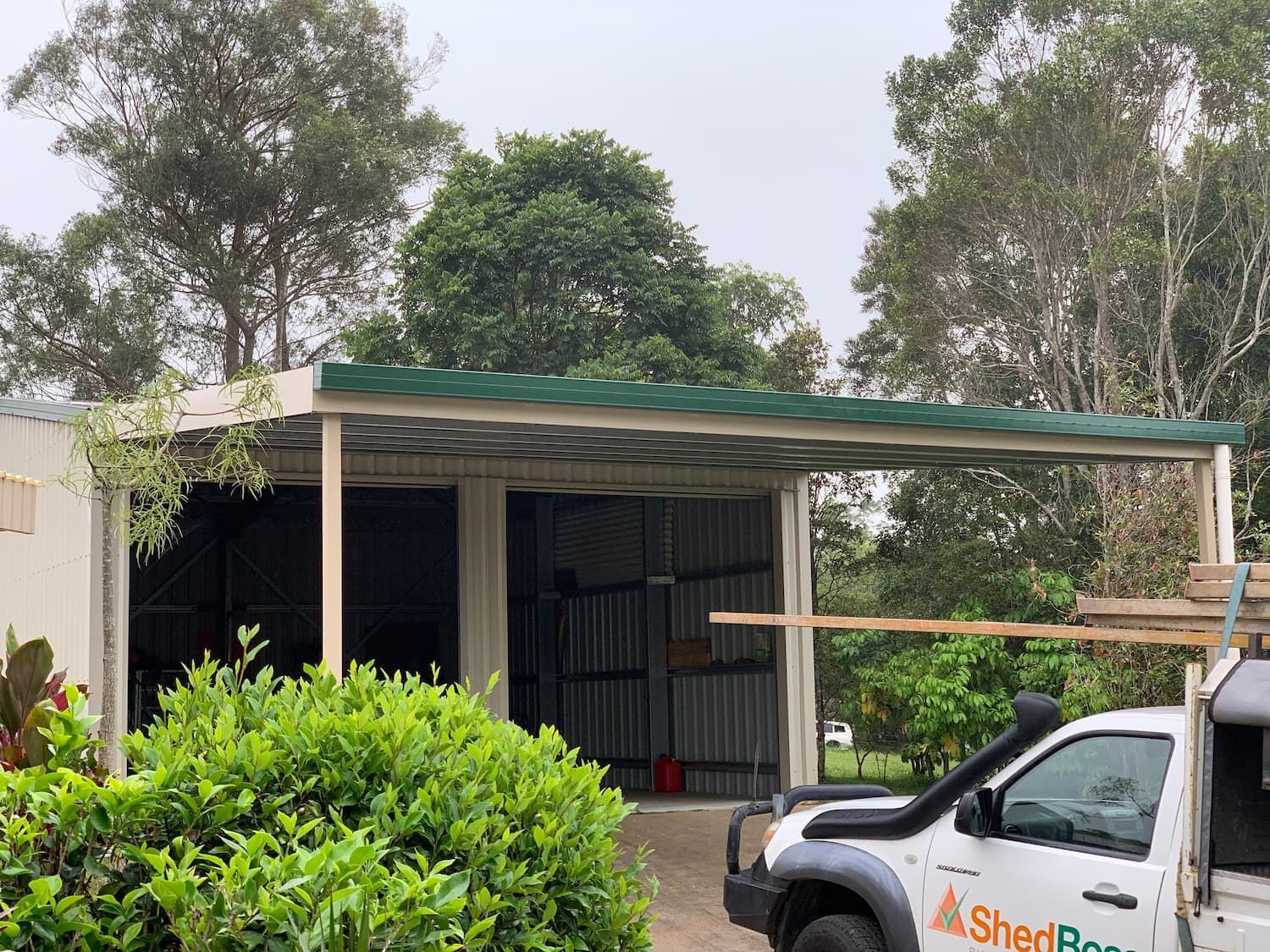 Green-roofed Shed With Open Doors, a White Truck Parked Nearby — ShedBoss in Atherton, QLD