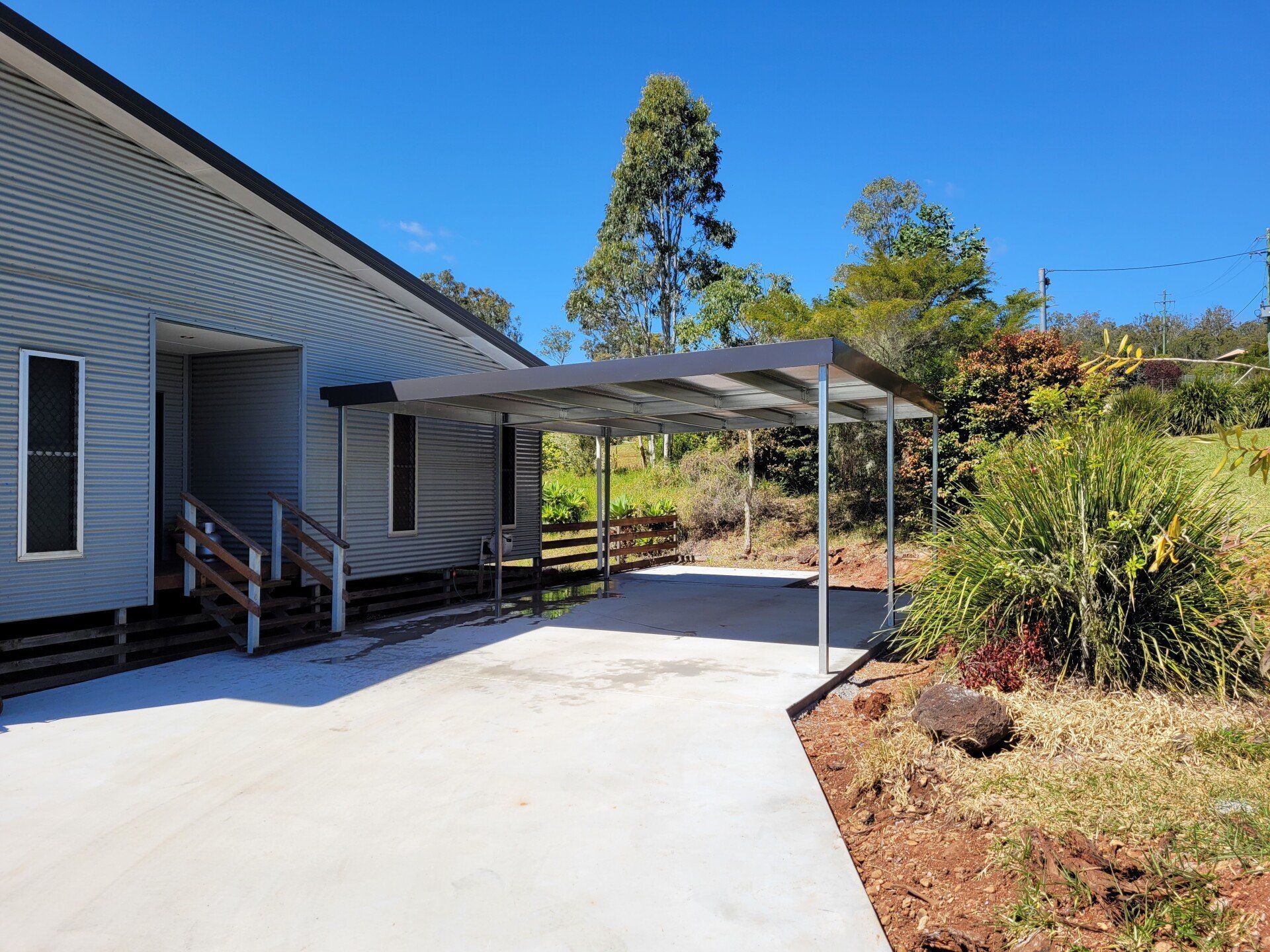 Carport Attached to a Light Blue House on a Sunny Day — ShedBoss in Atherton, QLD
