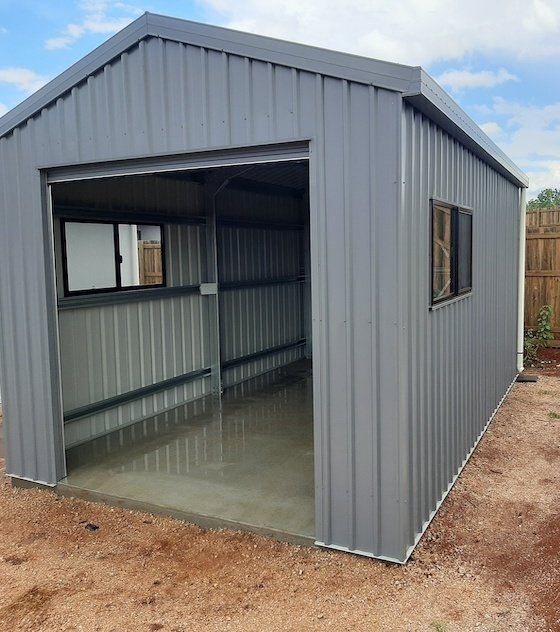 Gray Metal Shed With Open Garage Door and Two Windows on a Concrete Slab — ShedBoss in Atherton, QLD