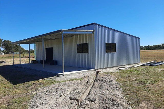 Metal Building With a Covered Porch on a Grassy Field Under a Bright Blue Sky — ShedBoss in Atherton, QLD