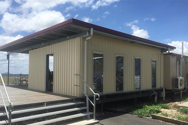 Tan Corrugated Metal Building With a Deck, Stairs, and Windows — ShedBoss in Atherton, QLD