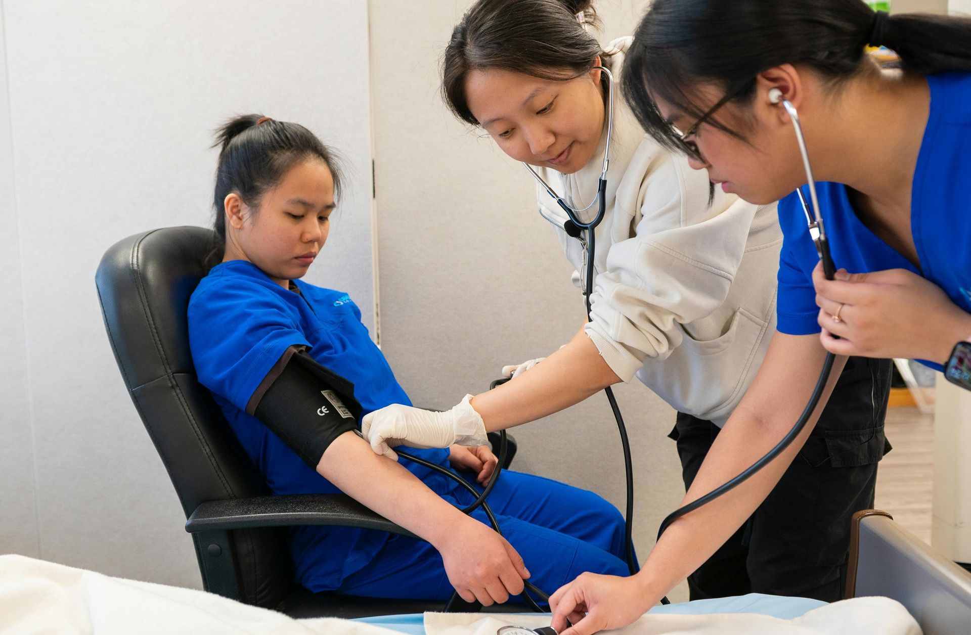 Nurse taking a child’s blood pressure while another clinician observes in a clinic room