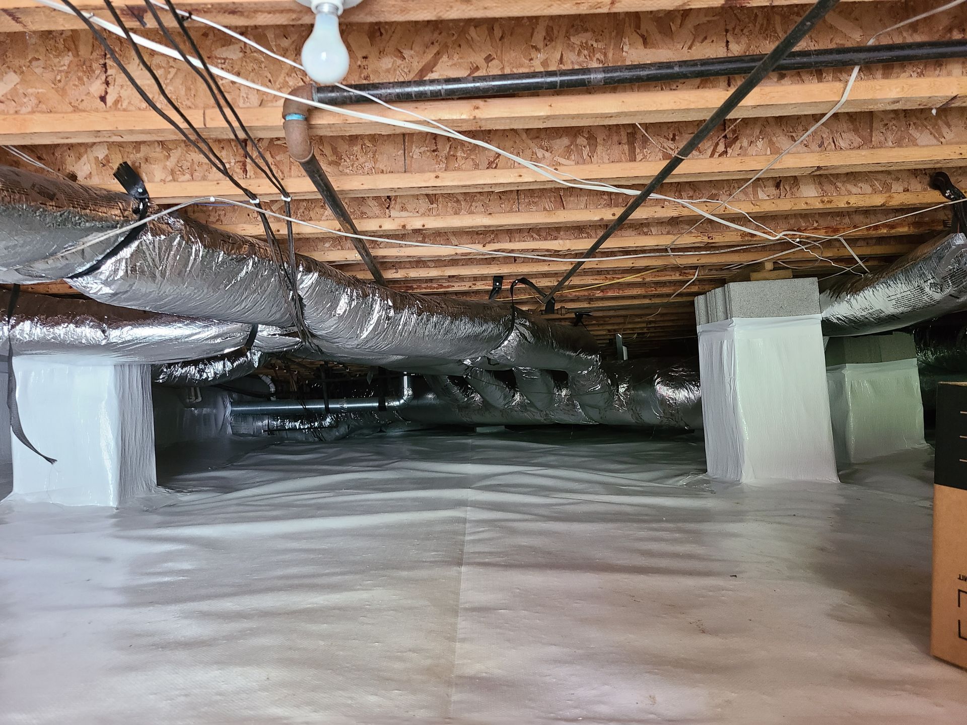 A ceiling with a lot of pipes and wires coming out of it.
