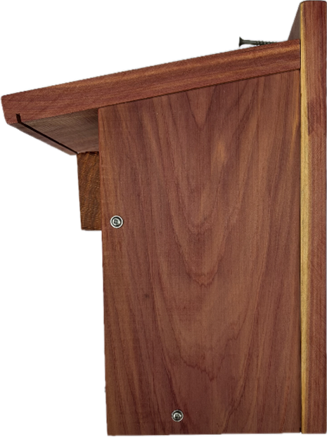 A wooden birdhouse with a roof and a nail in it