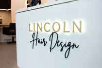 Lincoln Hair Design sign on a white counter in a salon interior