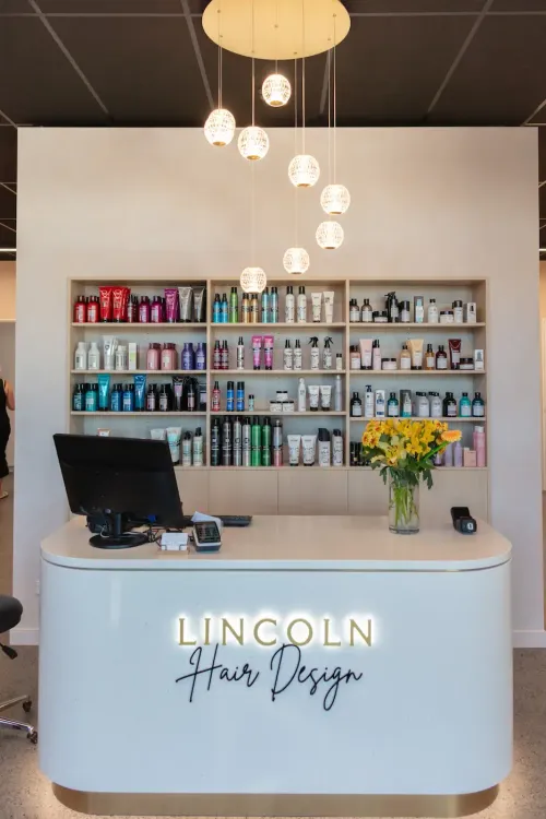 Hair salon reception desk with product shelves and hanging lights, labeled “Lincoln Hair Design”