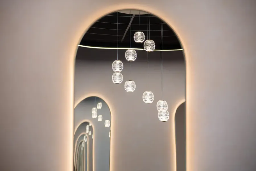 Arched hallway with glowing recessed frames and hanging glass pendant lights in a modern interior