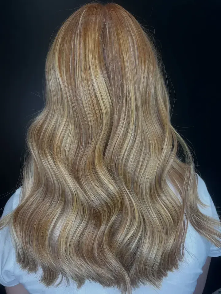 Blonde wavy hair shown from the back against a dark background