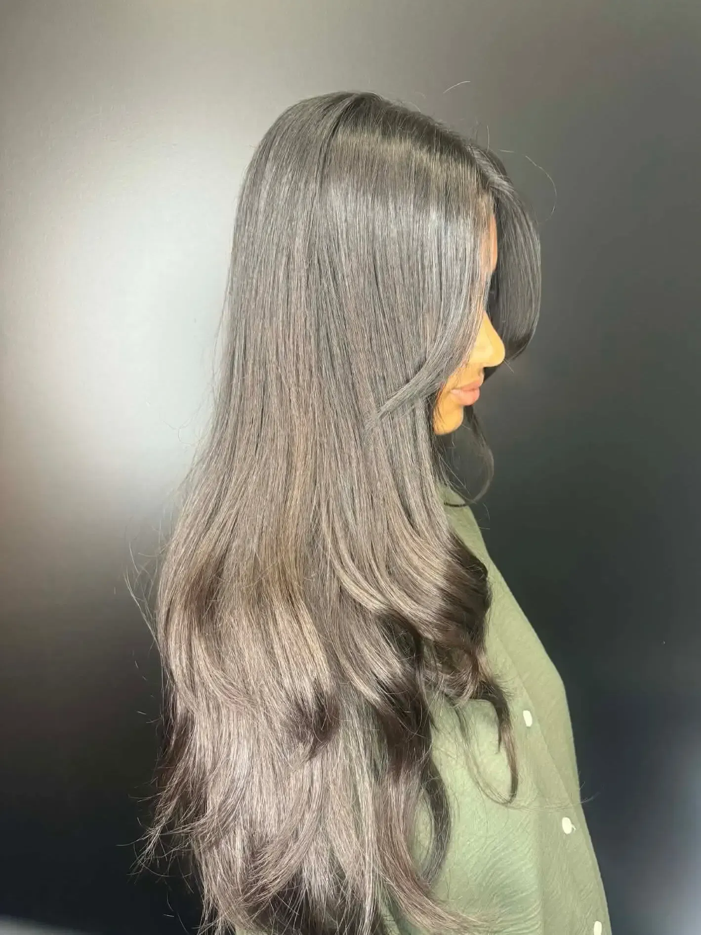 Side-profile portrait of a person with long black hair against a dark background