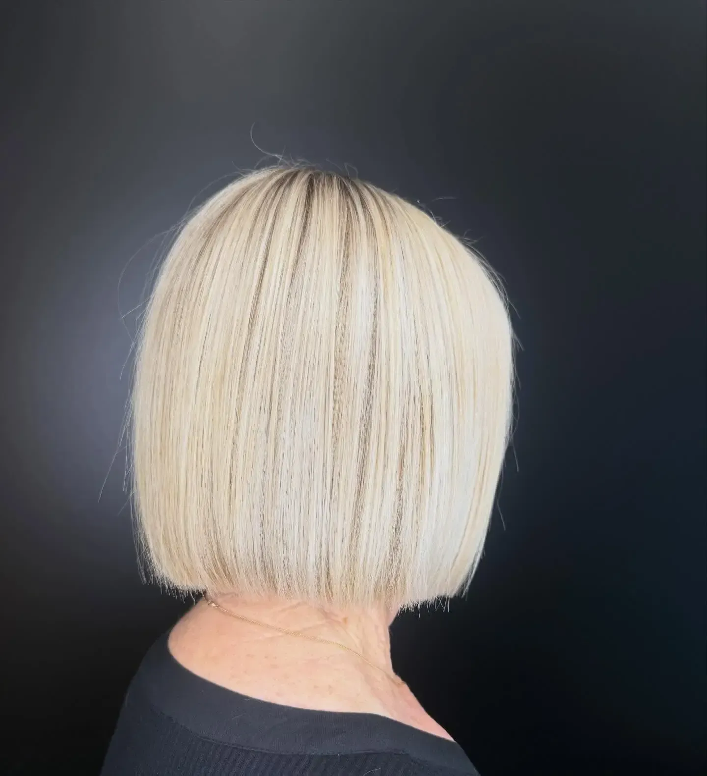 Back view of a short platinum blonde bob haircut against a black background