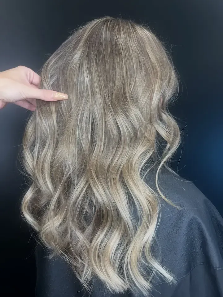 Wavy blonde hair styled to shoulder length, shown from the back against a dark background.