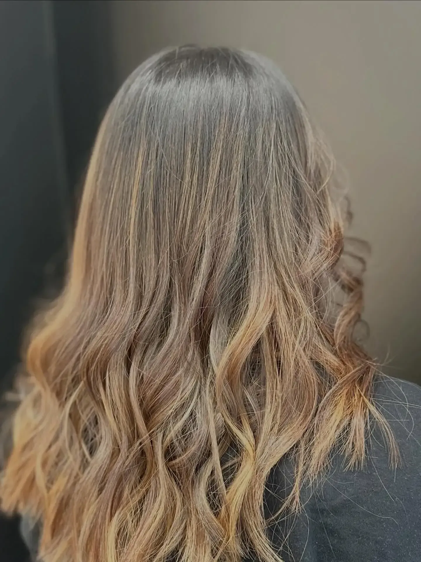 Wavy shoulder-length brown hair with blonde highlights against a dark background