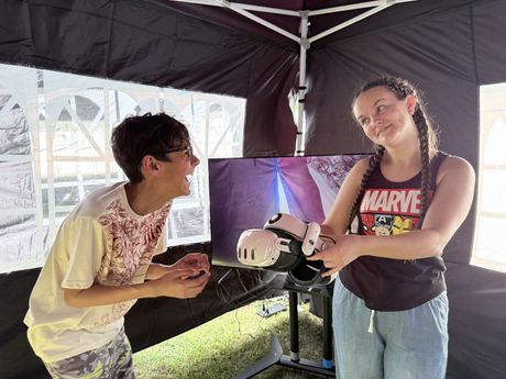 Two people chatting under a canopy beside a small robot display
