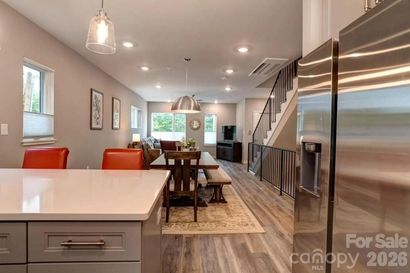 Bright modern kitchen with white cabinets, large island, pendant lights, and wood barstools