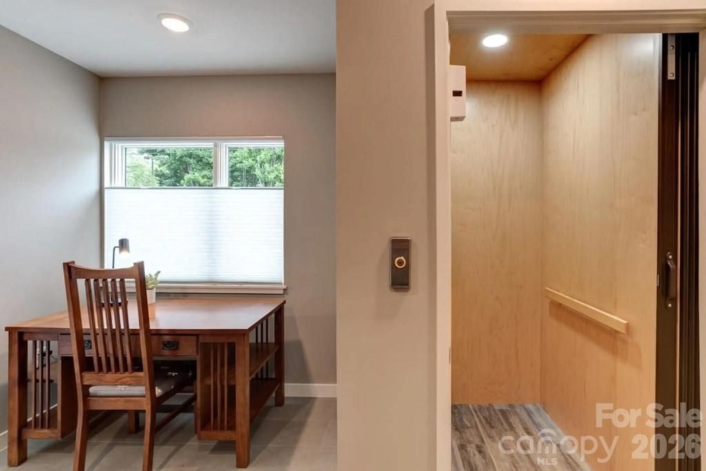 Dining area with wooden table and chairs beside a bright hallway with light wood paneling