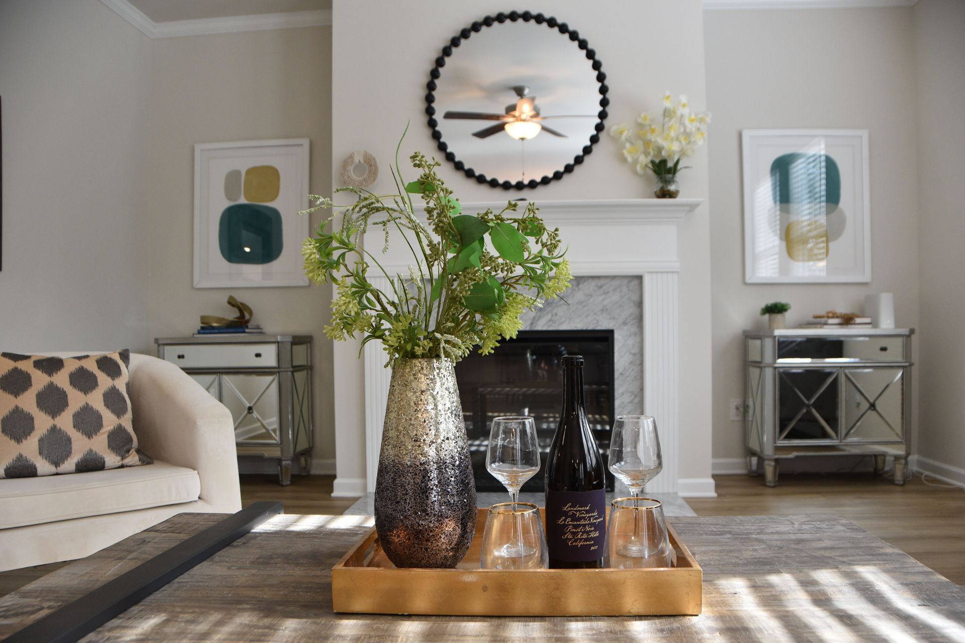 Stylish living room with fireplace, round mirror, and coffee table centerpiece with flowers and candles